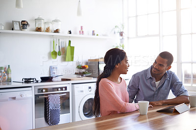Buy stock photo Shot of a young couple sitting at their dining table using a digital tablet