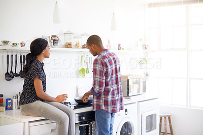 Buy stock photo Shot of a young couple enjoying cooking dinner together in their kitchen