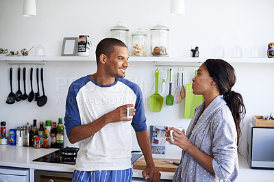 Buy stock photo Shot of a young couple talking and drinking coffee in the kitchen