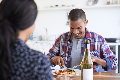 Buy stock photo Shot of a young couple talking together over dinner in their kitchen