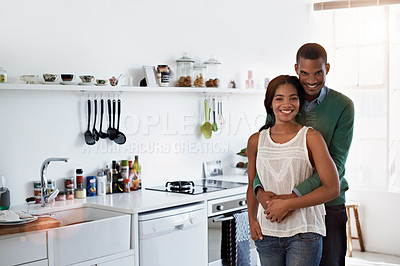 Buy stock photo Portrait of an affectionate young couple standing arm in arm in their home