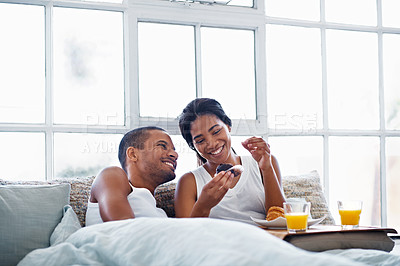 Buy stock photo Shot of a smiling young couple enjoying breakfast in bed together