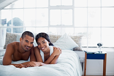Buy stock photo Portrait of a happy young couple lying in bed together