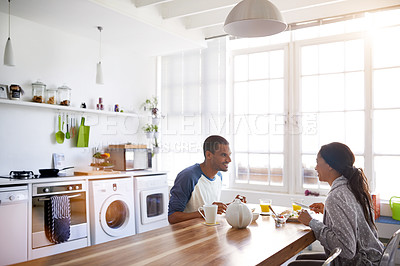Buy stock photo Shot of a young couple eating breakfast together in their kitchen