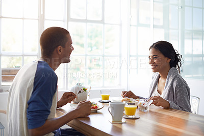 Buy stock photo Shot of a young couple eating breakfast together in their kitchen