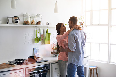 Buy stock photo Shot of an affectionate young couple hugging in the kitchen