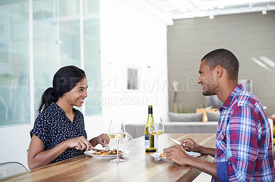 Buy stock photo Shot of a young couple eating dinner in their kitchen