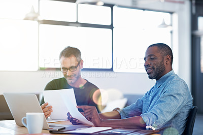 Buy stock photo Shot of two men working together at a table in an office