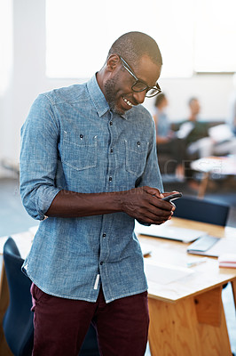 Buy stock photo Shot of a man standing in an office sending a text message