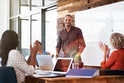 Buy stock photo Shot of a young man giving a whiteboard presentation to a group of coworkers in an office