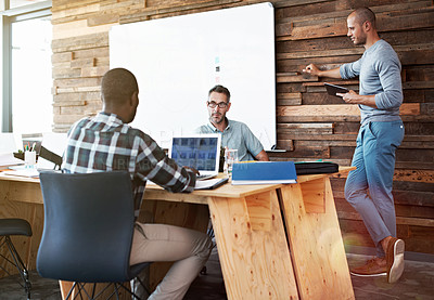 Buy stock photo Shot of three colleagues talking together while working in an office
