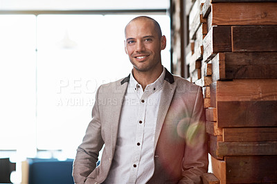 Buy stock photo Portrait of a handsome businessman leaning against a wall in an office