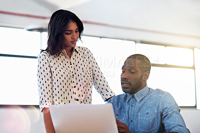 Buy stock photo Shot of two colleagues talking together over a laptop in an office