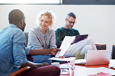 Buy stock photo Shot of two businesspeople looking over some paperwork in the office