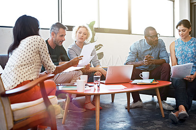 Buy stock photo Shot of a group of businesspeople looking over some paperwork in the office