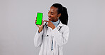 Green screen, phone and doctor in studio pointing for medical service, health app and mockup. Happy, space and black woman on cellphone for advertising, healthcare and telehealth on white background