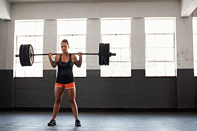 Buy stock photo Shot of a muscular young woman in a gym lifting a barbell