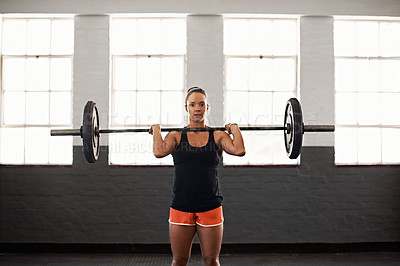 Buy stock photo Shot of a muscular young woman in a gym lifting a barbell