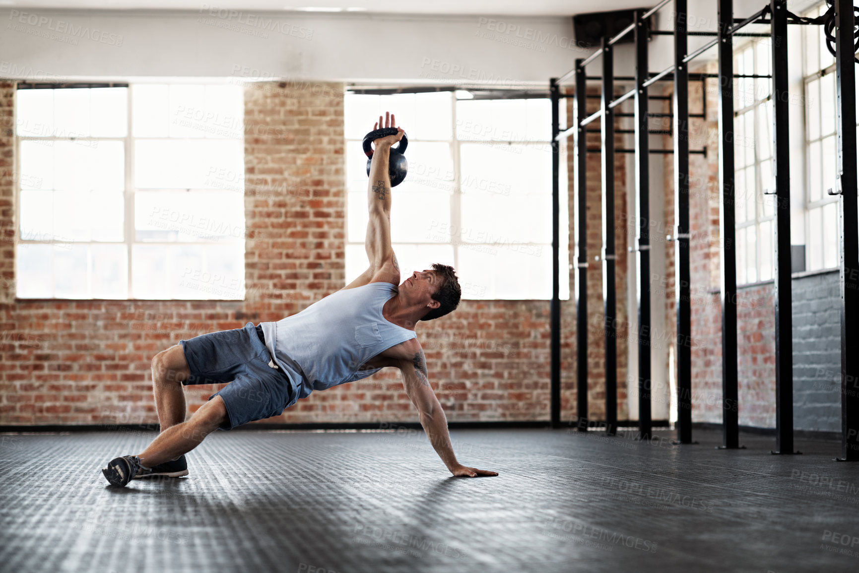 Buy stock photo Full length shot of a young man doing a workout with a kettlebell in a gym