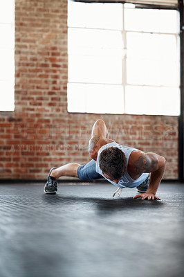 Buy stock photo Shot of a young man in a gym doing one-handed pushups