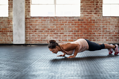 Buy stock photo Shot of a young woman in a gym doing pushups