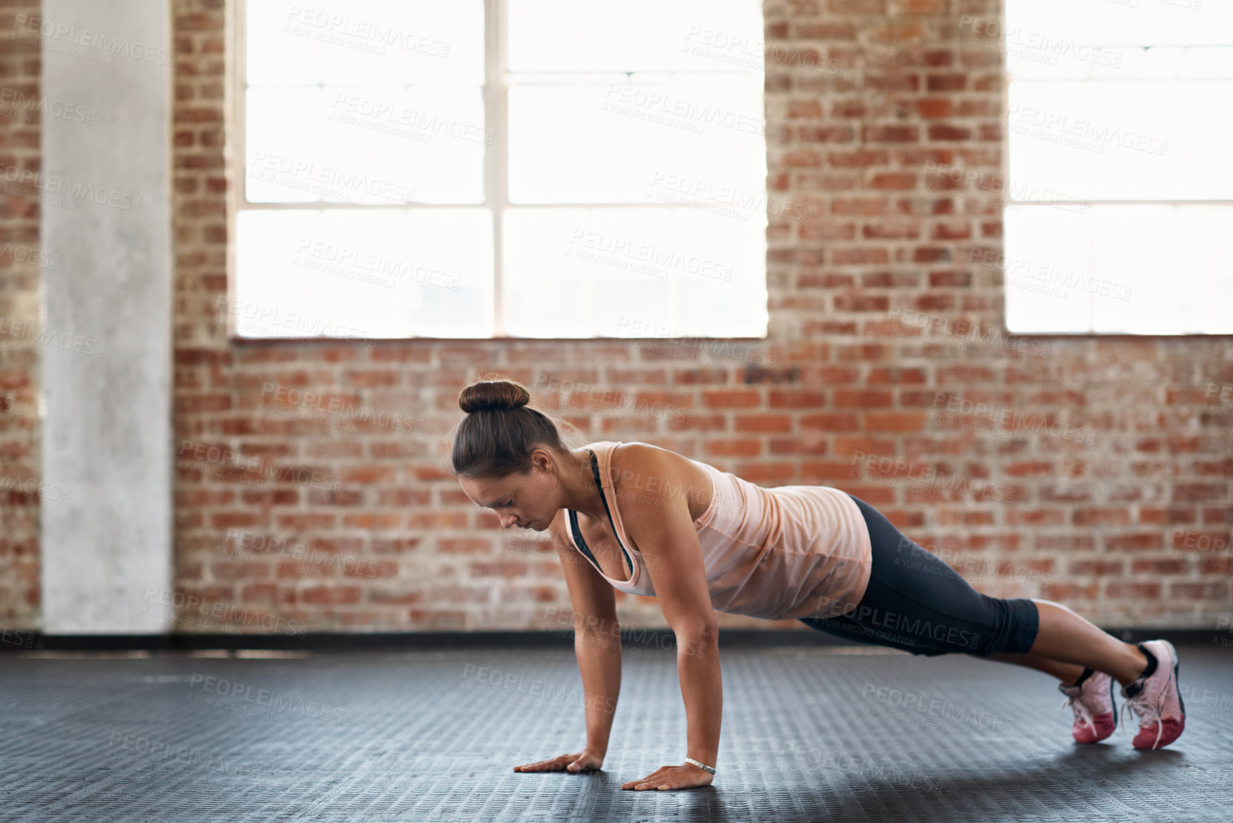 Buy stock photo Shot of a young woman in a gym doing pushups