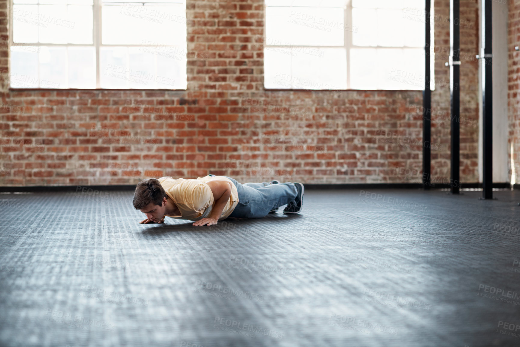 Buy stock photo Shot of a young man in a gym doing pushups