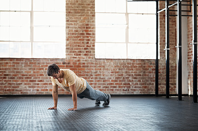 Buy stock photo Shot of a young man in a gym doing pushups