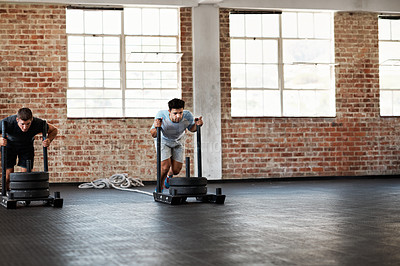 Buy stock photo Shot of two men in a crossfit class pushing weights across the floor