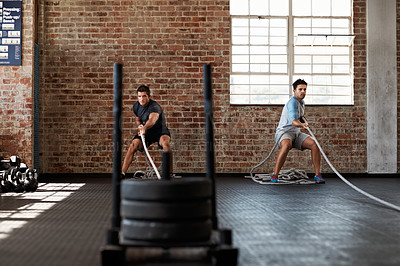 Buy stock photo Shot of two men pulling weights across the floor in a crossfit class