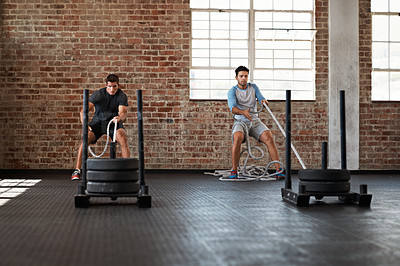 Buy stock photo Shot of two men pulling weights across the floor in a crossfit class