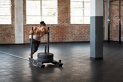 Buy stock photo Shot of a young woman pushing weights across the floor in a crossfit class