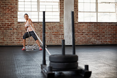 Buy stock photo Shot of a young woman pulling weights across the floor in a crossfit class