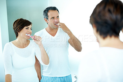 Buy stock photo Couple, mirror and cleaning with toothbrush for dental care, grooming and morning routine in home. Mature man, woman and reflection for brushing teeth, toothpaste and wellness in house bathroom