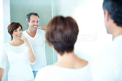 Buy stock photo Couple, mirror and brushing teeth for dental care, grooming and morning routine in home. Mature man, woman and reflection of smile with toothbrush, oral health and wellness or happy in house bathroom