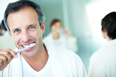 Buy stock photo Bathroom, oral hygiene and man with smile, brushing teeth and morning routine with partner in house. Couple, portrait and mature person with toothbrush for dental care, happy and wash mouth in home