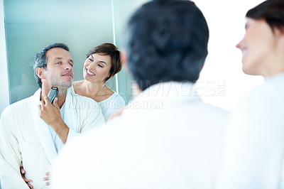 Buy stock photo Mirror, couple and shaving in bathroom with smile, hair removal and grooming for hygiene. Happy, people and reflection at house with trimmer, beard maintenance and facial shaver for morning routine