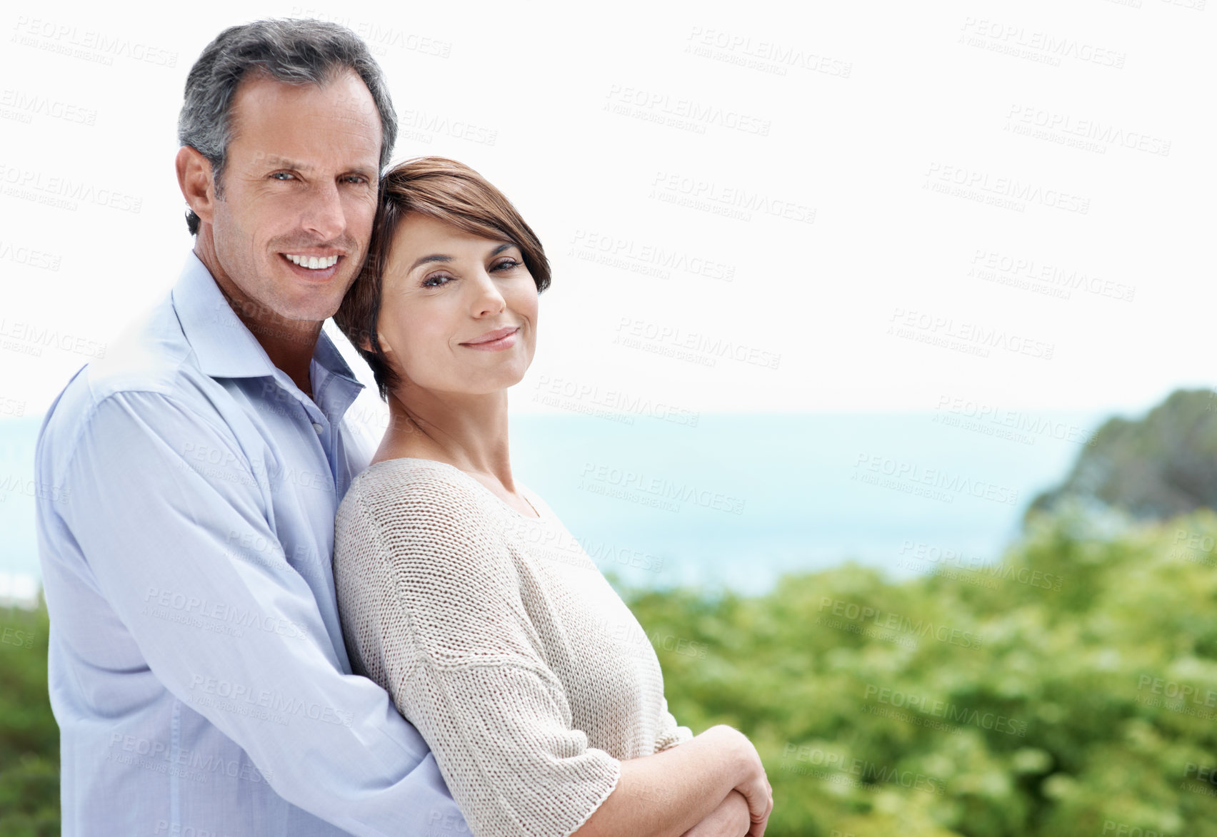 Buy stock photo Smile, hug and couple with care by ocean, loyalty or relationship commitment on vacation. Happy, mature man and woman embrace at sea for love, portrait or bonding together on holiday with space