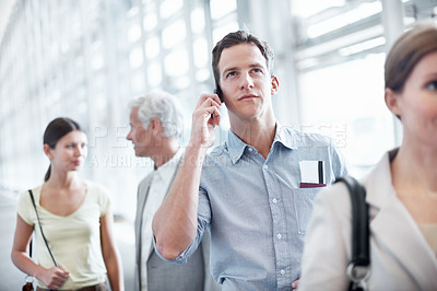 Buy stock photo Young business executive heading out on a business trip and talking on his mobile