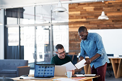Buy stock photo Shot of  two male coworkers talking together at a desk in an office