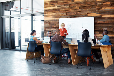 Buy stock photo Shot of a female office worker giving a financial presentation to her colleagues