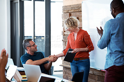 Buy stock photo Shot of two coworkers shaking hands during an office presentation