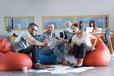 Buy stock photo Shot of a group of colleagues sitting in bean bag chairs while working in an office