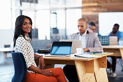 Buy stock photo Portrait of an office worker sitting at her desk with colleagues in the background