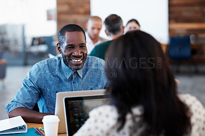 Buy stock photo Shot of two coworkers talking together over a laptop at a desk in an office