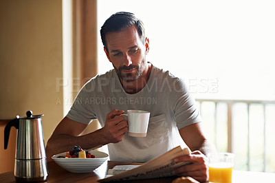 Buy stock photo Cropped shot of a handsome man eating breakfast while reading the paper