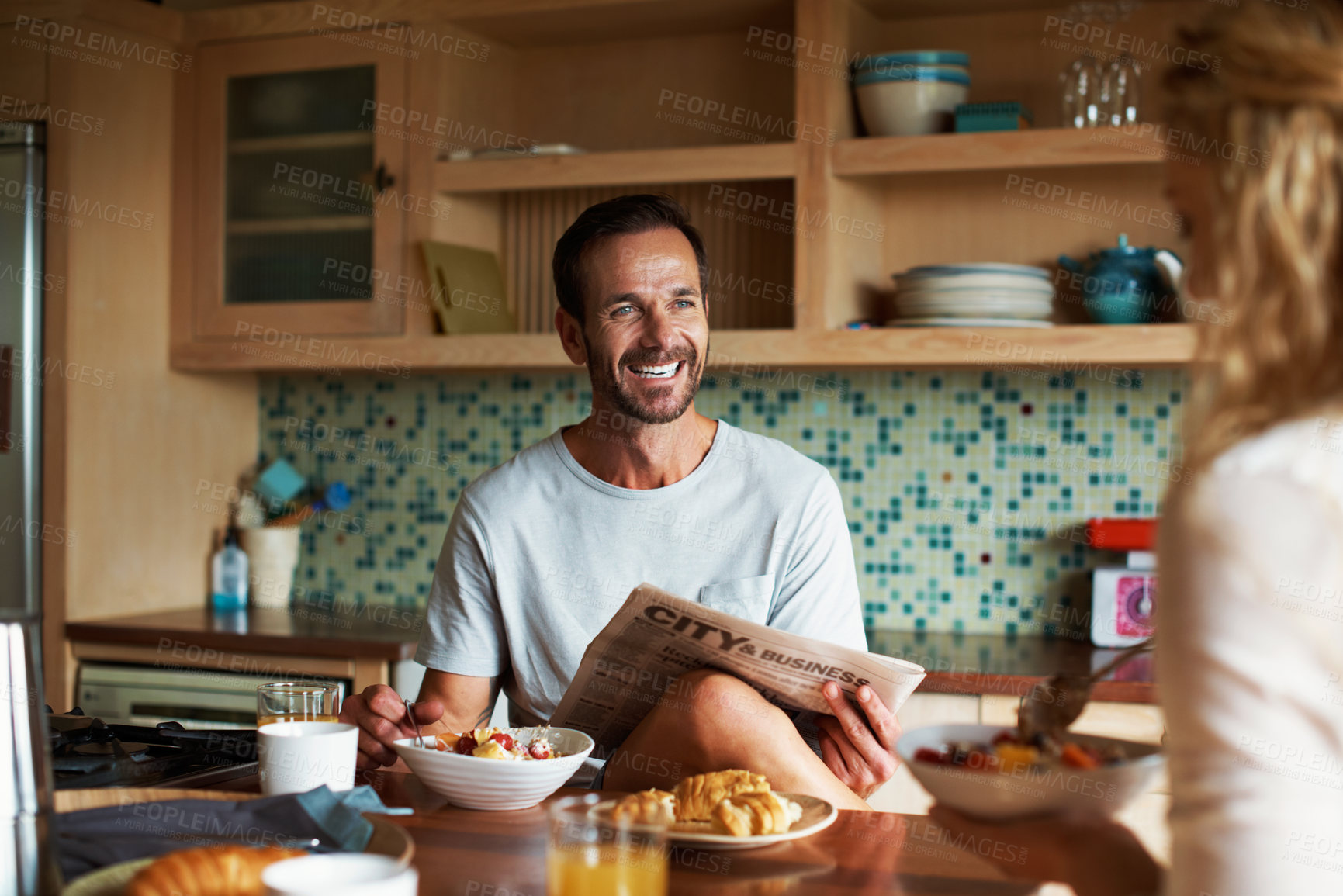 Buy stock photo Newspaper, couple and man in kitchen for talking, bonding and eating together in morning. Breakfast, happy and people in home for conversation, chat and coffee for marriage, connection and love