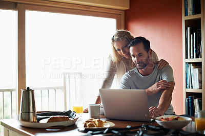 Buy stock photo Cropped shot of a couple using a laptop in the middle of breakfast