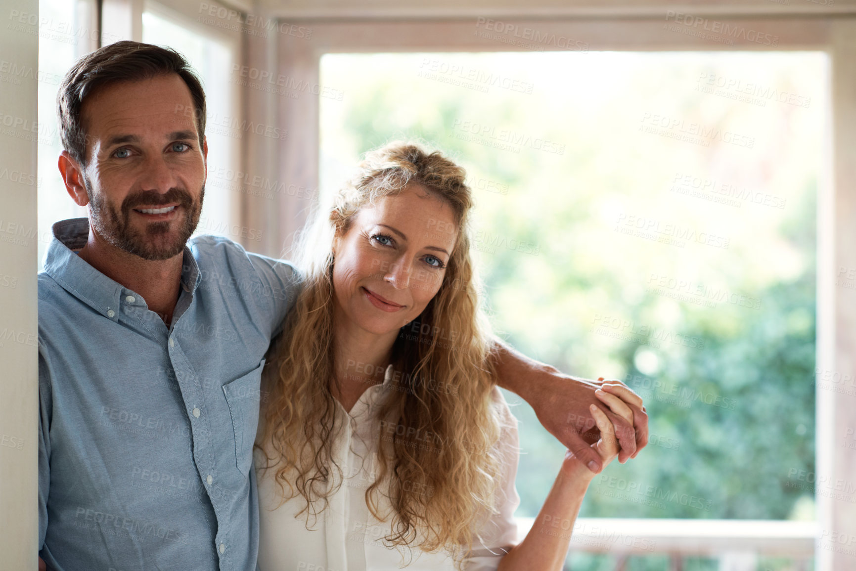 Buy stock photo Happy couple, portrait and bonding in home, holding hands or love connection with partner on weekend. People, embrace and smile with spouse, care and together in house and relationship commitment