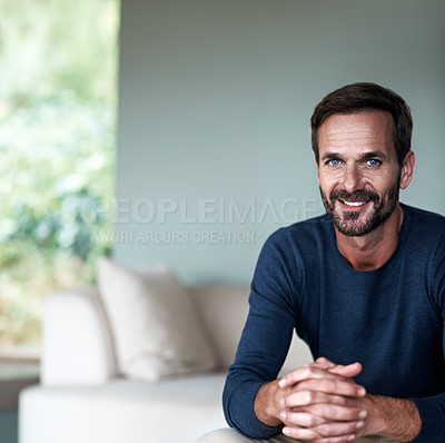 Buy stock photo Cropped portrait of a handsome man sitting on his living room sofa